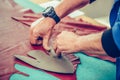 Close up hands of an experienced shoemaker measuring and cutting leather in a workshop