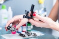 Close-up of the hands of a female artist preparing a professional tattoo machine