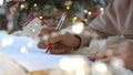 Close up hands of female writing letter and wish list at Christmas Eve. Girl writing in notebook. Woman hand holding pen Royalty Free Stock Photo