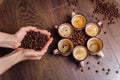 Close-up of the hands of a girl who sprinkles roasted coffee beans to the floor. On the floor there are cups of freshly brewed Royalty Free Stock Photo