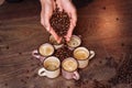 Close-up of the hands of a girl who sprinkles roasted coffee beans to the floor. On the floor there are cups of freshly brewed