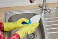 Close up hands in gloves of woman washing dishes in kitchen with sponge Royalty Free Stock Photo