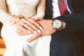 Close-up of the hands of the groom with the clock and the bride