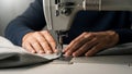 Close-up of hands guiding fabric through a sewing machine, demonstrating precision and craftsmanship in textile work Royalty Free Stock Photo