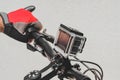 Close-up, the hands of a guy in red gloves on the handlebars of a bicycle with an action camera. On a light background