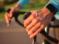 Close up of hands on handlebar. Professional cyclist with smartwatch cycling ooutdoors at sunset Royalty Free Stock Photo