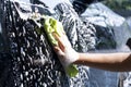 Close-up hands hold sponge or microfiber cloth for washing and cleaning car in sunny day