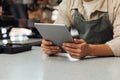 Close-up of hands holding a digital tablet. Unrecognizable bartender in an apron holding a portable computer at the counter Royalty Free Stock Photo