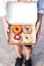 Close up hands holding four pieces of totally different colorful and delicious looking donuts in ecological carton box. appetising