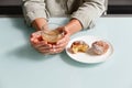 close up of hands holding glass cup of coffee with milk, and plate with two curd muffins, one of them is started Royalty Free Stock Photo