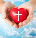 Close up of hands holding heart with cross symbol Royalty Free Stock Photo