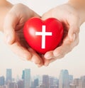 Close up of hands holding heart with cross symbol Royalty Free Stock Photo