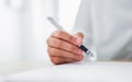 Close-up of hands holding pen and writing on notepad, paper on desk.