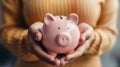 Close-up of hands holding a pink piggy bank for savings. Focus on financial planning and security. Simple, modern, and Royalty Free Stock Photo