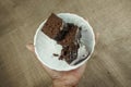 Close-up of hands holding plate of brownie cake on burlap background