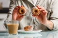 close up of hands holding and showing two curd muffins over plate with another cake, and glass cup of coffee with milk standing Royalty Free Stock Photo