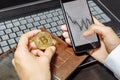 Close-up of hands holding smartphone and bitcoin. Smartphone with cash trading chart on-screen. Crypto currency concept. Financial