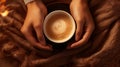 Close up of hands holding steaming hot drink coffee or hot chocolate in a coffee mug