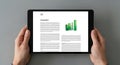 Hands holding tablet displaying financial report with bar chart and data tables Royalty Free Stock Photo