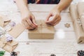 Close up of hands holding wrapping gift box on wooden table with xmas decoration