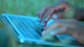 Close-up, Hands of an Indian Paren Sitting on the Grass Typing Text on the Laptop Keyboard