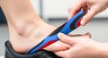 Hands placing blue red black shoe insert into foot Royalty Free Stock Photo