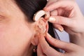 Close up of hands inserting hearing aid in ear