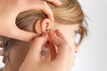 Close up of hands inserting a hearing aid in ear Royalty Free Stock Photo