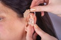 Close up of hands inserting hearing aid in ear Royalty Free Stock Photo