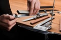 Close-up on hands inserting a whetstone into a manual sharpener machine