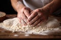 close-up of hands kneading pizza dough on a floury wooden board