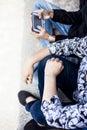 Close up of only hands and legs of teenager sitting on a wall and using smart phones and spending time with friends.