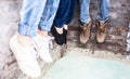 Close up of only hands and legs of teenager sitting on a wall and using smart phones and spending time with friends.