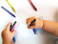 Close up of the hands of a little child drawing a flower with color pencils Royalty Free Stock Photo