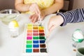 Close-up on the hands of little children who paint eggs with special paints