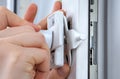 Close-up hands of locksmith installing window limiter on plasti