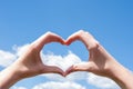 Close-up of hands making a heart symbol on a background of blue sky and clouds. Love, charity, valentines day concept Royalty Free Stock Photo