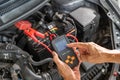 Close up hands of a male mechanic using a battery tester to check on a car battery status Royalty Free Stock Photo