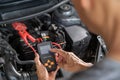 Close up hands of a male auto mechanic using a battery tester to test on car battery status Royalty Free Stock Photo