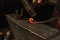 Close-up hands of male blacksmith forge an iron product in a blacksmith. Hammer, red hot metal and anvil. Concept of Royalty Free Stock Photo