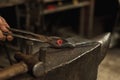 Close-up hands of male blacksmith forge an iron product in a blacksmith. Hammer, red hot metal and anvil. Concept of Royalty Free Stock Photo