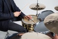 Close up of hands of male drummer holdning drumsticks sitting and playing drums on white background