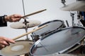 Close up of hands of male drummer holdning drumsticks sitting and playing drums on white background