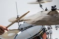 Close up of hands of male drummer holdning drumsticks sitting and playing drums on white background