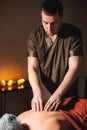 Close-up of the hands of a male masseur doing back massage to a girl at the spa. Low key high contrast shallow depth of Royalty Free Stock Photo