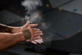 Close up of hands of man applying white dust of magnesia, chalk on hands before climbing wall in bouldering center