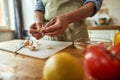 Close up of hands of man in apron peeling garlic while preparing healthy meal, soup in the kitchen. Cooking at home Royalty Free Stock Photo