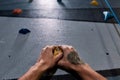 Close up of hands of man climbing up on rock wall in gym. Bouldering training concept Royalty Free Stock Photo