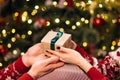 Close-up hands of man giving festive box with Christmas present to woman sitting at dinner feast table during holiday Royalty Free Stock Photo