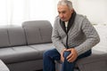 close up hands man with his knee joint pain in sofa, pain in the elderly, health care. Grandfather with knee pain Royalty Free Stock Photo